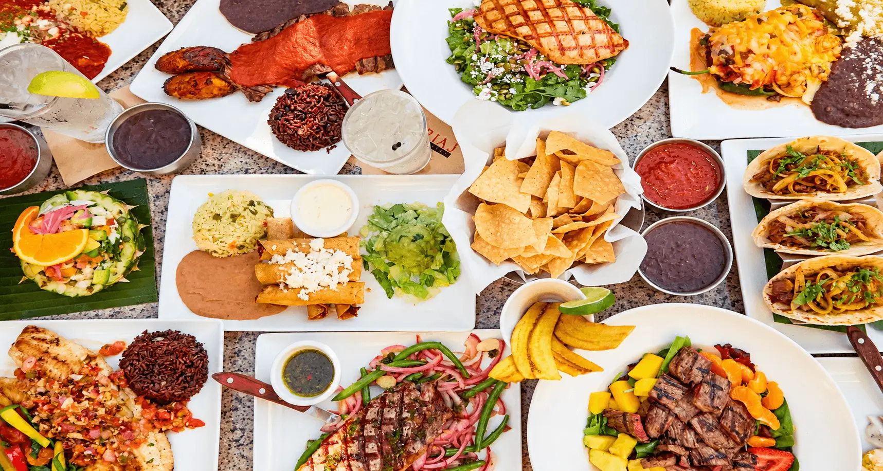 Overhead view of Gloria's Latin Cuisine dishes, including Latin-inspired entrees, tacos, salads, chips, and salsa, featured in a Magic Logix restaurant marketing case study.